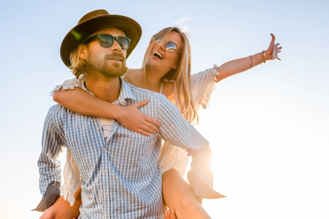 Attractive happy couple laughing traveling in summer by sea, man and woman wearing sunglasses